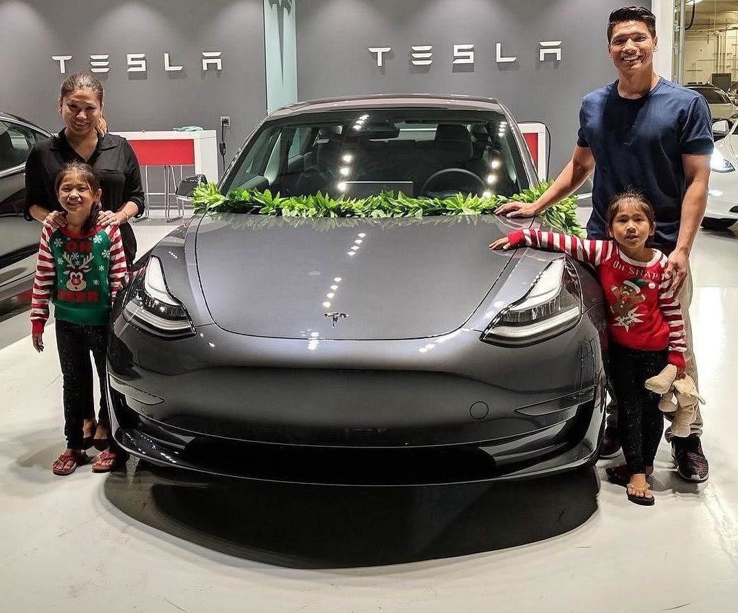 Family gathered around their Tesla at a showroom